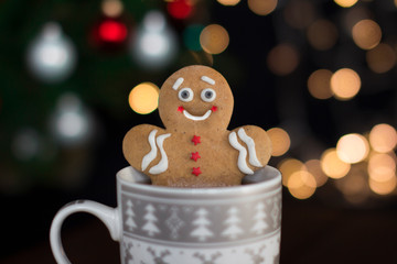 smiling gingerbread man cookie in a cup with hot chocolate