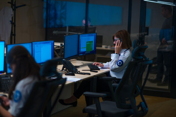 Security guard monitoring modern CCTV cameras in a surveillance room. Group of security guards sitting and monitoring.