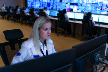 In the System Control Room, Technical Operator Works at His Workstation with Multiple Displays, Security guard working on multiple monitors...