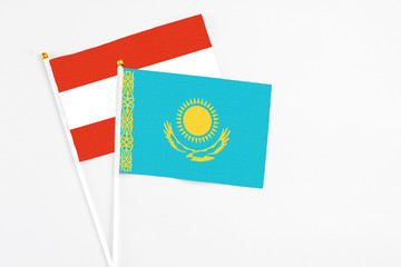 Kazakhstan and Austria stick flags on white background. High quality fabric, miniature national flag. Peaceful global concept.White floor for copy space.