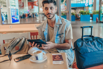 Handsome man drinking coffee at airport waiting room