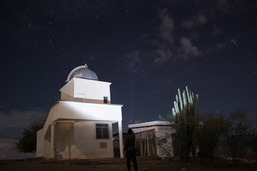 A Lonely man lighting up The Astronomical Observatory and a spined cactus in starry night at...
