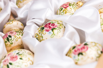 Christmas tree beige balls and top with painted roses and glitter on a white silk cloth backround - soft focus