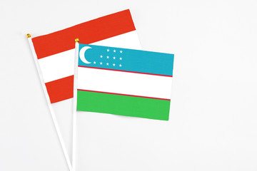 Uzbekistan and Austria stick flags on white background. High quality fabric, miniature national flag. Peaceful global concept.White floor for copy space.
