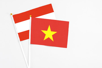 Vietnam and Austria stick flags on white background. High quality fabric, miniature national flag. Peaceful global concept.White floor for copy space.