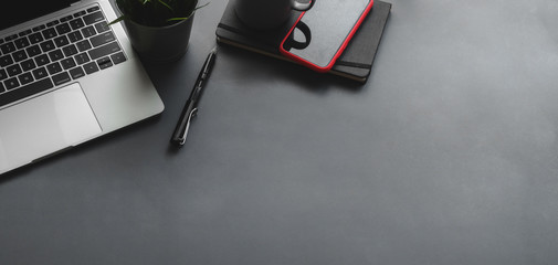 Top view of dark stylish workplace with laptop computer and office supplies on black table