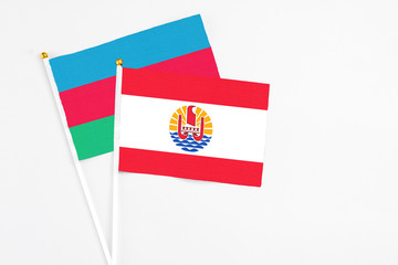 French Polynesia and Azerbaijan stick flags on white background. High quality fabric, miniature national flag. Peaceful global concept.White floor for copy space.
