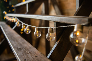 Christmas garland of light bulbs hanging from a wooden staircase. Festive home decoration....