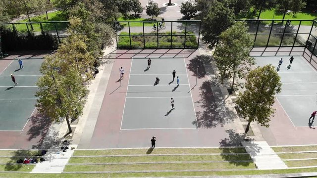 Aerial view of three volleyball courts with young people playing, drone hovering