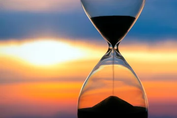 Foto op Canvas Hourglass on the background of a sunset. The value of time in life. An eternity.. © photosaint