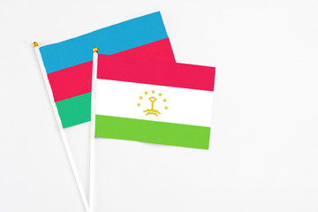 Tajikistan and Azerbaijan stick flags on white background. High quality fabric, miniature national flag. Peaceful global concept.White floor for copy space.