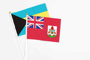 Fototapeta premium Bermuda and Bahamas stick flags on white background. High quality fabric, miniature national flag. Peaceful global concept.White floor for copy space.
