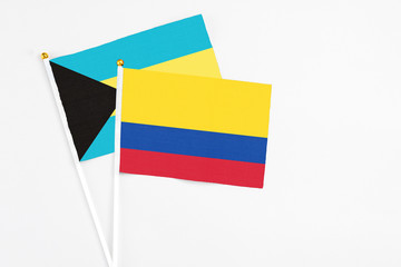 Colombia and Bahamas stick flags on white background. High quality fabric, miniature national flag. Peaceful global concept.White floor for copy space.