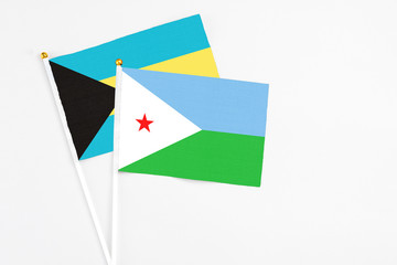 Djibouti and Bahamas stick flags on white background. High quality fabric, miniature national flag. Peaceful global concept.White floor for copy space.