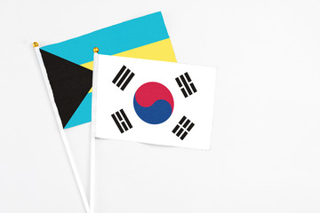 South Korea and Bahamas stick flags on white background. High quality fabric, miniature national flag. Peaceful global concept.White floor for copy space.