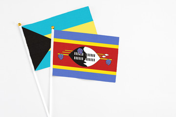 Swaziland and Bahamas stick flags on white background. High quality fabric, miniature national flag. Peaceful global concept.White floor for copy space.