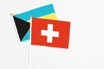 Switzerland and Bahamas stick flags on white background. High quality fabric, miniature national flag. Peaceful global concept.White floor for copy space.