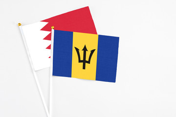 Barbados and Bahrain stick flags on white background. High quality fabric, miniature national flag. Peaceful global concept.White floor for copy space.