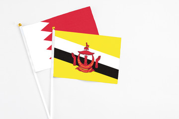 Brunei and Bahrain stick flags on white background. High quality fabric, miniature national flag. Peaceful global concept.White floor for copy space.