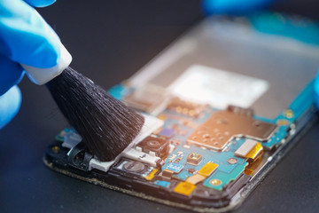 Asian Technician repair and cleaning dirty micro circuit main board of smartphone electronic...