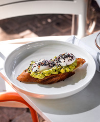 Haute cuisine - grilled sandwich with avocado guacamole sauce and two sunny side up eggs outside restaurant in a sunny day