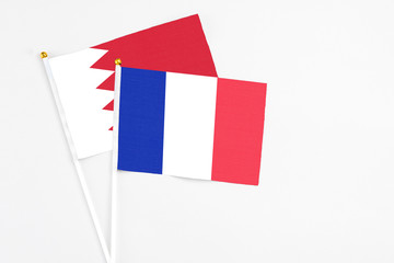 France and Bahrain stick flags on white background. High quality fabric, miniature national flag. Peaceful global concept.White floor for copy space.