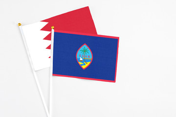 Guam and Bahrain stick flags on white background. High quality fabric, miniature national flag. Peaceful global concept.White floor for copy space.