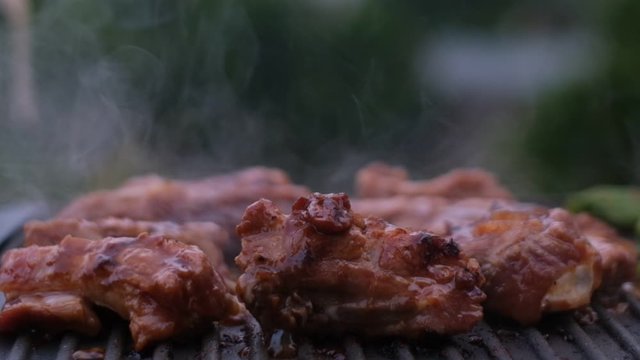 Stock footage HD. Cooked beef steak or pork ribs, toasting meat on a metal electric grill. Royalty high-quality free stock video footage of electric grill stove grilled meat with garden background