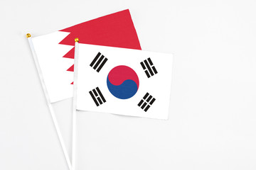 South Korea and Bahrain stick flags on white background. High quality fabric, miniature national flag. Peaceful global concept.White floor for copy space.