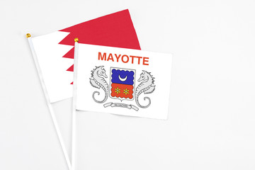 Mayotte and Bahrain stick flags on white background. High quality fabric, miniature national flag. Peaceful global concept.White floor for copy space.