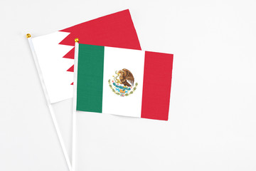 Mexico and Bahrain stick flags on white background. High quality fabric, miniature national flag. Peaceful global concept.White floor for copy space.