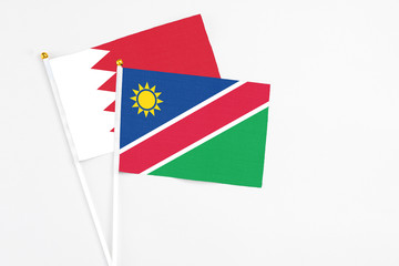 Namibia and Bahrain stick flags on white background. High quality fabric, miniature national flag. Peaceful global concept.White floor for copy space.