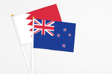 New Zealand and Bahrain stick flags on white background. High quality fabric, miniature national flag. Peaceful global concept.White floor for copy space.