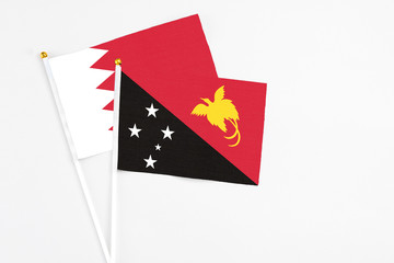Papua New Guinea and Bahrain stick flags on white background. High quality fabric, miniature national flag. Peaceful global concept.White floor for copy space.