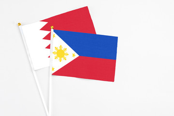 Philippines and Bahrain stick flags on white background. High quality fabric, miniature national flag. Peaceful global concept.White floor for copy space.