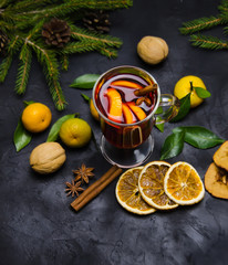 Obraz na płótnie Canvas Christmas mulled wine with spices and oranges and tangerines on a wooden rustic table. Traditional hot drink for Christmas. Selective focus.