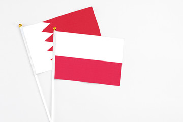 Poland and Bahrain stick flags on white background. High quality fabric, miniature national flag. Peaceful global concept.White floor for copy space.