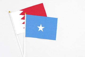 Somalia and Bahrain stick flags on white background. High quality fabric, miniature national flag. Peaceful global concept.White floor for copy space.