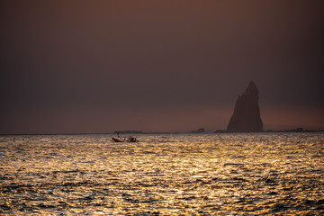 Naklejka na ściany i meble Boat and sunset in the ocean from far away