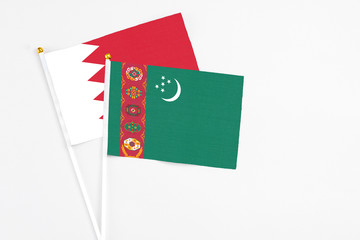 Turkmenistan and Bahrain stick flags on white background. High quality fabric, miniature national flag. Peaceful global concept.White floor for copy space.