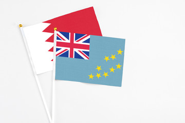 Fototapeta premium Tuvalu and Bahrain stick flags on white background. High quality fabric, miniature national flag. Peaceful global concept.White floor for copy space.