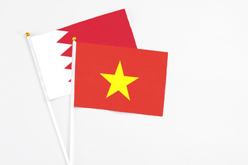 Vietnam and Bahrain stick flags on white background. High quality fabric, miniature national flag. Peaceful global concept.White floor for copy space.