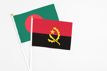 Angola and Bangladesh stick flags on white background. High quality fabric, miniature national flag. Peaceful global concept.White floor for copy space.