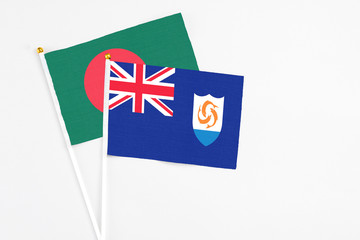 Fototapeta premium Anguilla and Bangladesh stick flags on white background. High quality fabric, miniature national flag. Peaceful global concept.White floor for copy space.