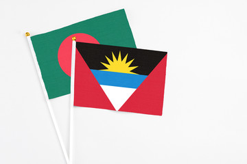 Antigua and Barbuda and Bangladesh stick flags on white background. High quality fabric, miniature national flag. Peaceful global concept.White floor for copy space.