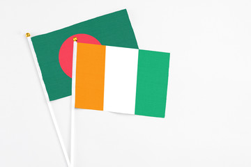 Cote D'Ivoire and Bangladesh stick flags on white background. High quality fabric, miniature national flag. Peaceful global concept.White floor for copy space.