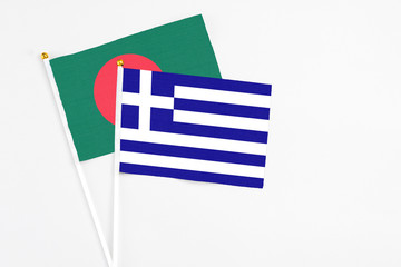 Greece and Bangladesh stick flags on white background. High quality fabric, miniature national flag. Peaceful global concept.White floor for copy space.