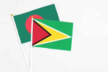 Guyana and Bangladesh stick flags on white background. High quality fabric, miniature national flag. Peaceful global concept.White floor for copy space.