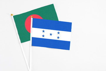 Honduras and Bangladesh stick flags on white background. High quality fabric, miniature national flag. Peaceful global concept.White floor for copy space.