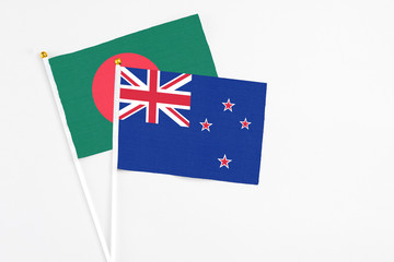 Fototapeta premium New Zealand and Bangladesh stick flags on white background. High quality fabric, miniature national flag. Peaceful global concept.White floor for copy space.